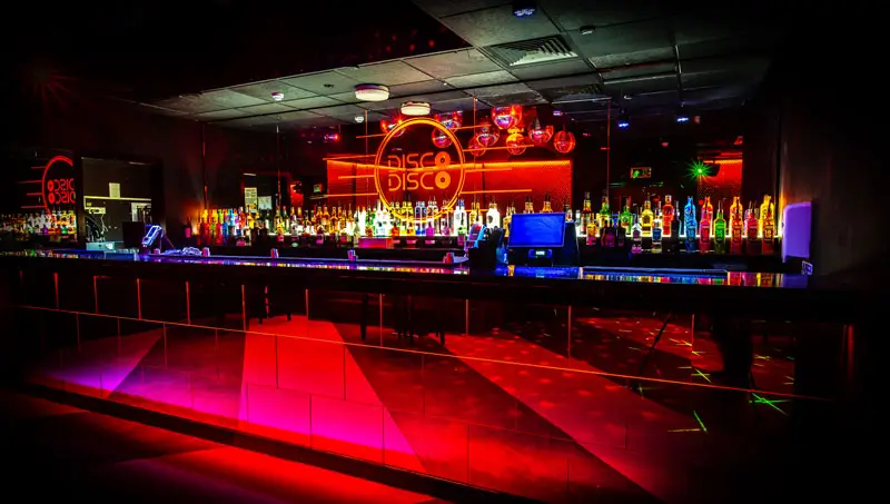 Bar lit in red under the Disco Disco sign